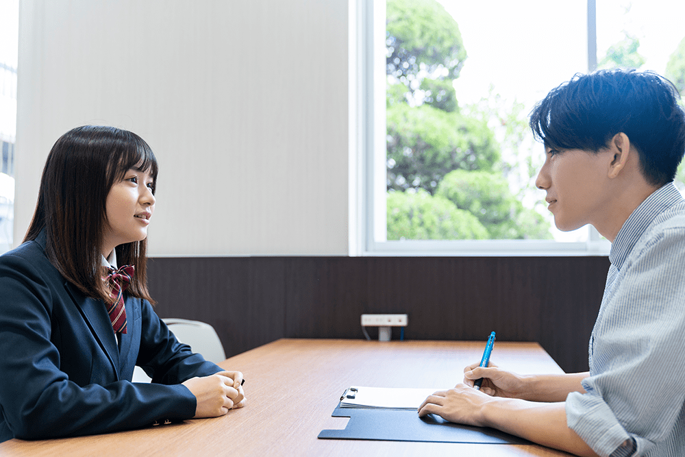 面談する高校生 生徒と同じ目線で問い合う